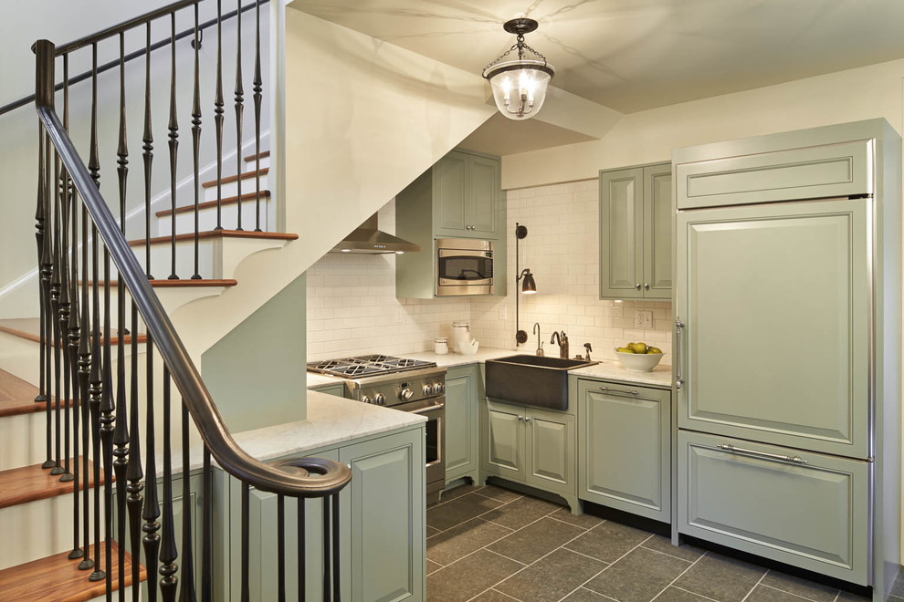 Example of a classic u-shaped kitchen design in Seattle with a farmhouse sink, raised-panel cabinets, green cabinets, beige backsplash, subway tile backsplash and paneled appliances