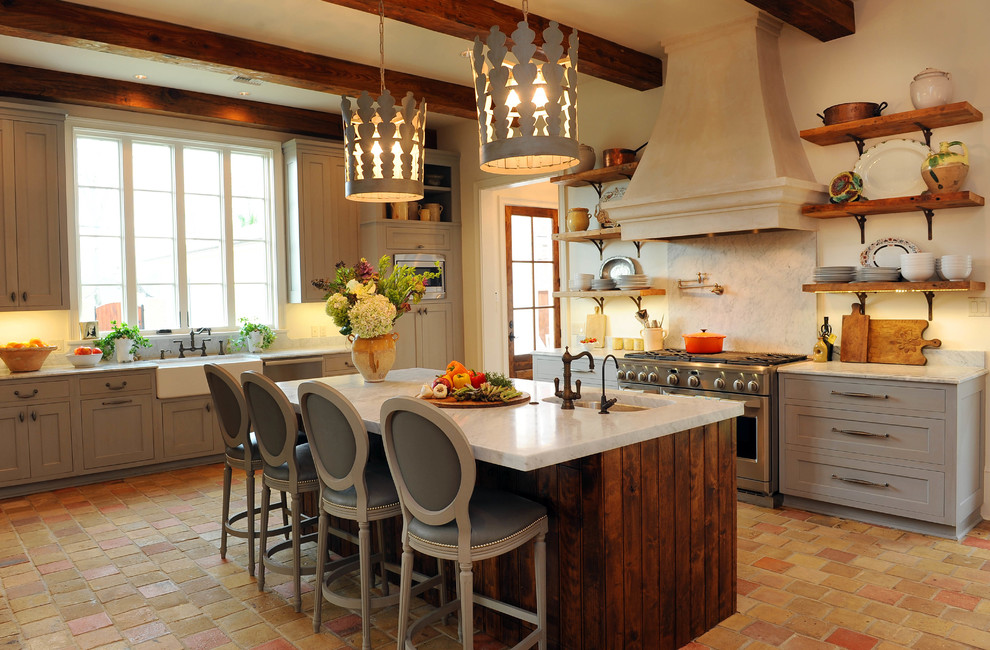 Example of a large tuscan l-shaped terra-cotta tile eat-in kitchen design in New Orleans with a farmhouse sink, distressed cabinets, marble countertops, white backsplash, stone slab backsplash and an island