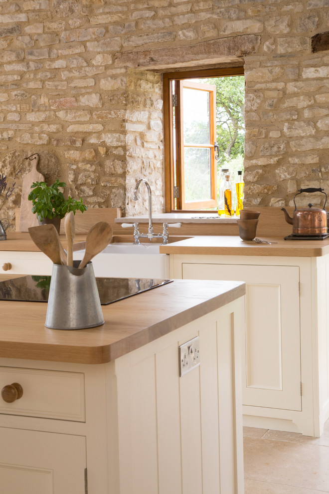 This is an example of a large rural l-shaped open plan kitchen in Other with a belfast sink, white cabinets, wood worktops, ceramic flooring, an island, stainless steel appliances and beaded cabinets.