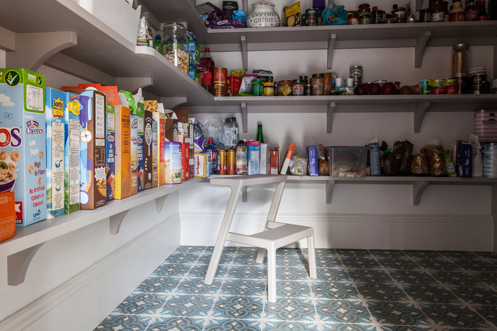 Idée de décoration pour une grande cuisine américaine tradition en L avec un évier de ferme, un placard à porte affleurante, des portes de placard grises, un plan de travail en quartz, une crédence blanche, une crédence en carrelage métro, un électroménager noir, un sol en terrazzo, îlot et un sol multicolore.