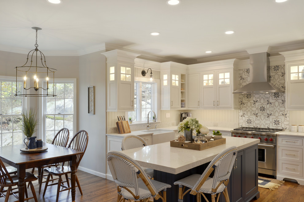 Eat-in kitchen - mid-sized traditional u-shaped medium tone wood floor and brown floor eat-in kitchen idea in New York with a farmhouse sink, beaded inset cabinets, white cabinets, quartzite countertops, gray backsplash, wood backsplash, stainless steel appliances and an island