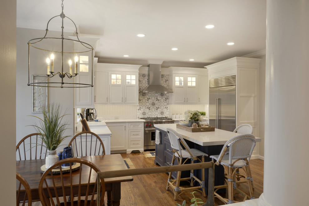 Klassisk inredning av ett mellanstort kök, med en rustik diskho, luckor med profilerade fronter, vita skåp, bänkskiva i kvartsit, grått stänkskydd, stänkskydd i trä, rostfria vitvaror, mellanmörkt trägolv, en köksö och brunt golv