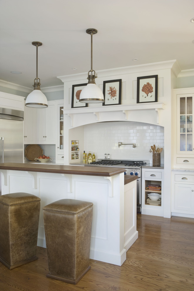 Klassische Küche mit weißen Schränken, Küchenrückwand in Weiß, Rückwand aus Metrofliesen, Küchengeräten aus Edelstahl und braunem Holzboden in Atlanta