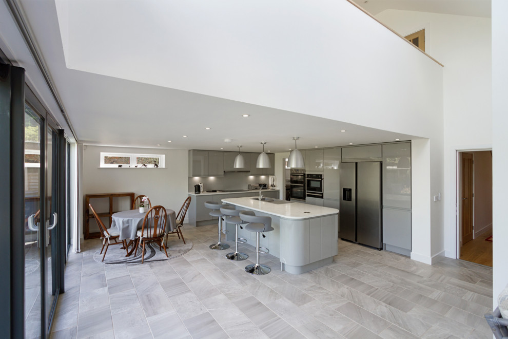 Inspiration for a medium sized modern l-shaped open plan kitchen in West Midlands with an integrated sink, flat-panel cabinets, grey cabinets, marble worktops, grey splashback, glass sheet splashback, stainless steel appliances, an island, grey floors and white worktops.
