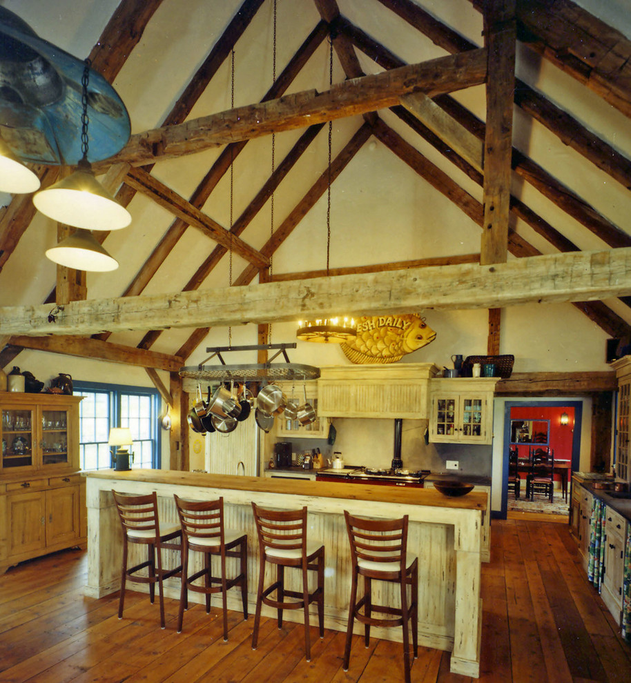 Foto på ett stort lantligt kök, med en rustik diskho, luckor med profilerade fronter, skåp i slitet trä, bänkskiva i täljsten, grönt stänkskydd, stänkskydd i sten, mellanmörkt trägolv och en köksö