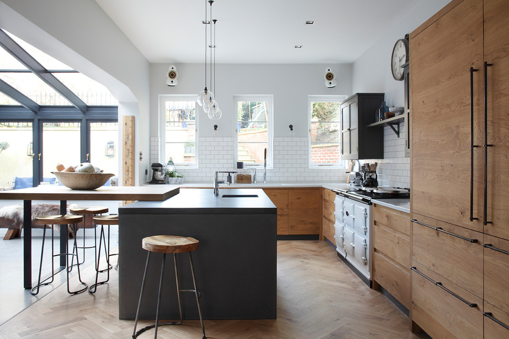 Moderne Wohnküche mit Betonarbeitsplatte, Küchenrückwand in Weiß, Rückwand aus Keramikfliesen, weißen Elektrogeräten, hellem Holzboden, Kücheninsel, Unterbauwaschbecken, flächenbündigen Schrankfronten, hellbraunen Holzschränken und beigem Boden in Surrey