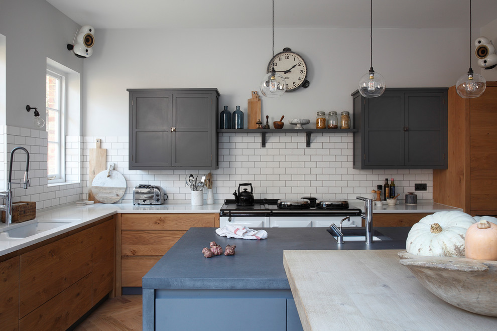 Industrial Wohnküche mit Doppelwaschbecken, grauen Schränken, Betonarbeitsplatte, Küchenrückwand in Weiß, Rückwand aus Keramikfliesen, weißen Elektrogeräten, hellem Holzboden und Kücheninsel in Surrey