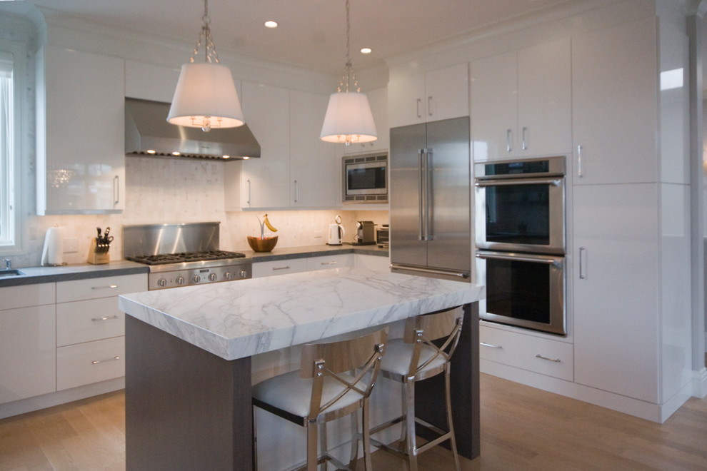 Inspiration for a large transitional u-shaped light wood floor eat-in kitchen remodel in San Francisco with a single-bowl sink, flat-panel cabinets, white cabinets, marble countertops, stone tile backsplash, stainless steel appliances and an island
