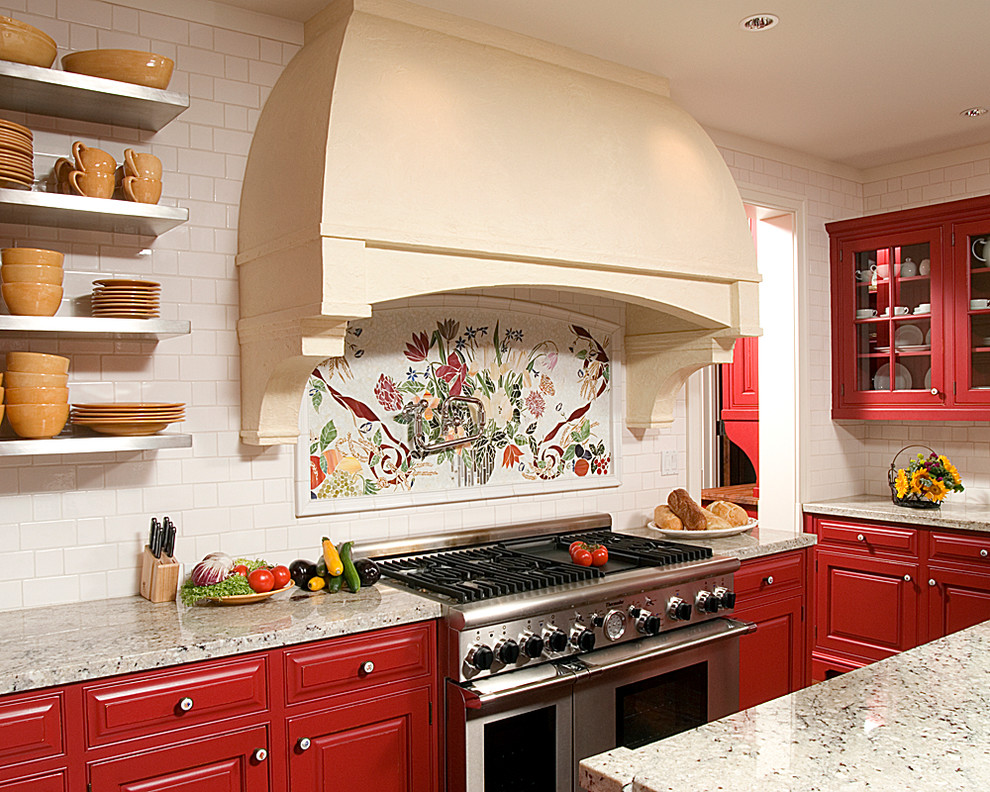 Klassische Küche mit roten Schränken, Granit-Arbeitsplatte, Kücheninsel, Kassettenfronten, bunter Rückwand und Küchengeräten aus Edelstahl in Sonstige