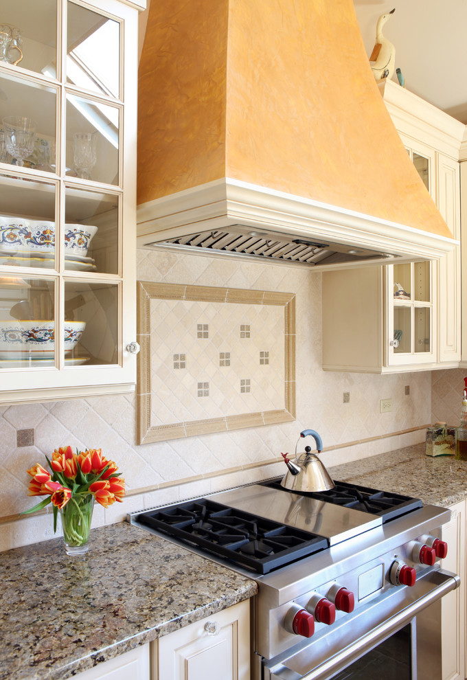 Inspiration for a mid-sized rustic l-shaped eat-in kitchen remodel in Chicago with glass-front cabinets, stainless steel appliances, white cabinets, granite countertops, an island, beige backsplash and stone tile backsplash