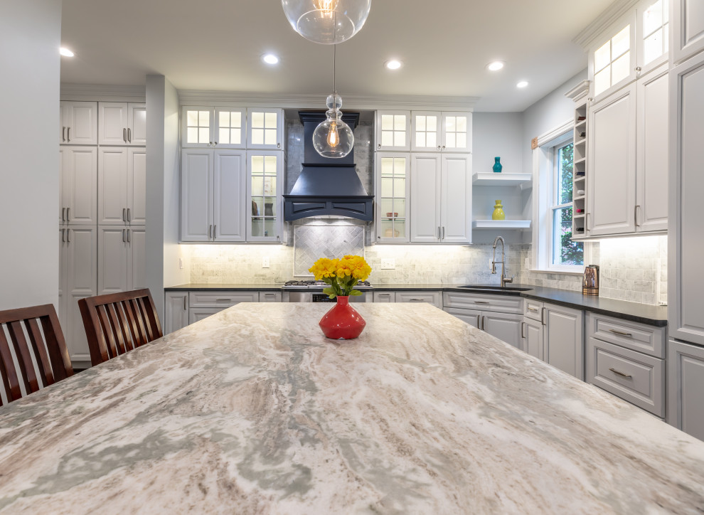 Modern inredning av ett litet flerfärgad flerfärgat kök och matrum, med vita skåp, bänkskiva i kvartsit, grått stänkskydd, rostfria vitvaror, mellanmörkt trägolv, en halv köksö och brunt golv