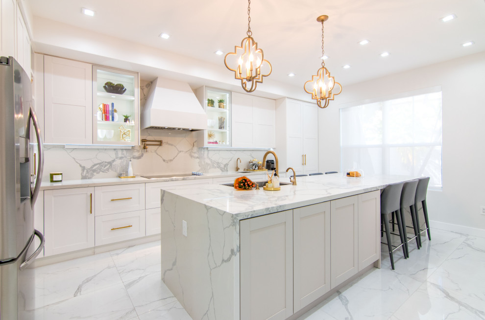 Design ideas for a large classic l-shaped open plan kitchen in Miami with a submerged sink, shaker cabinets, white cabinets, engineered stone countertops, white splashback, porcelain splashback, stainless steel appliances, porcelain flooring, an island, white worktops and white floors.