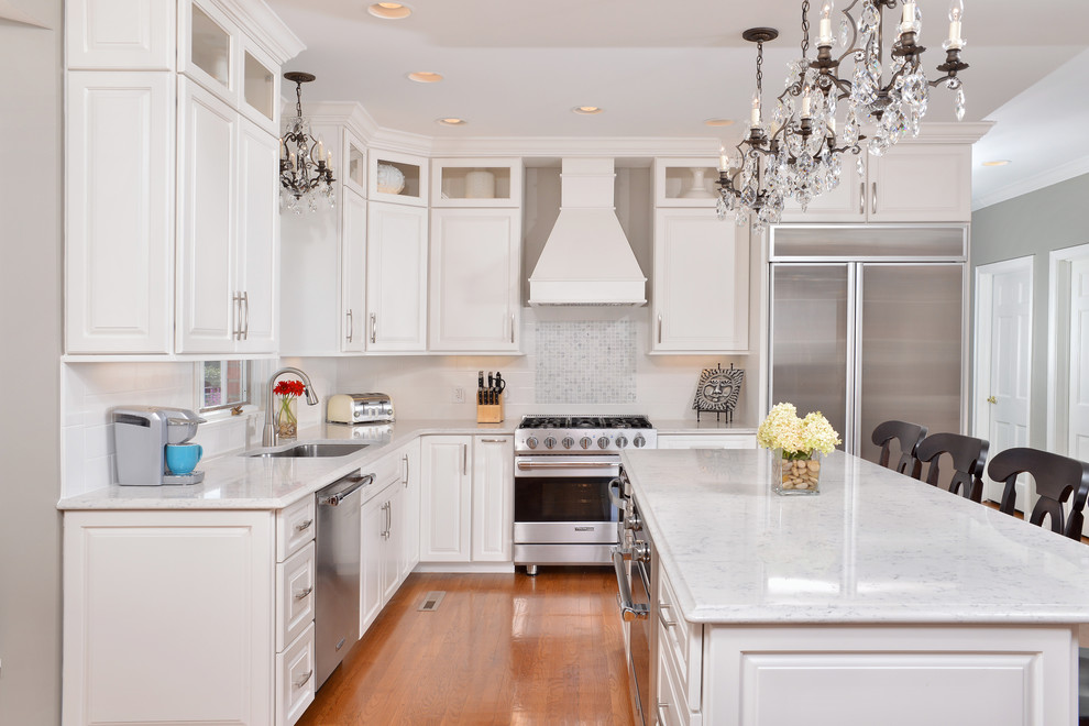 Photo of a traditional l-shaped kitchen in Cleveland with raised-panel cabinets, white cabinets, white splashback and stainless steel appliances.
