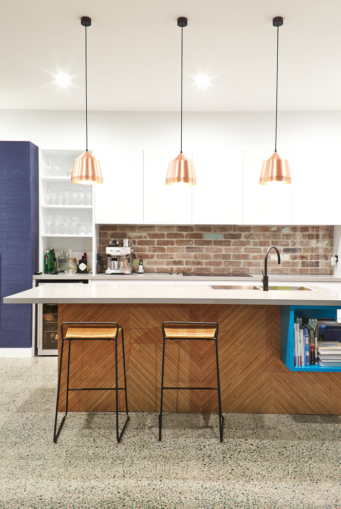 Modern inredning av ett mellanstort kök, med en undermonterad diskho, vita skåp, rostfria vitvaror, betonggolv och en köksö