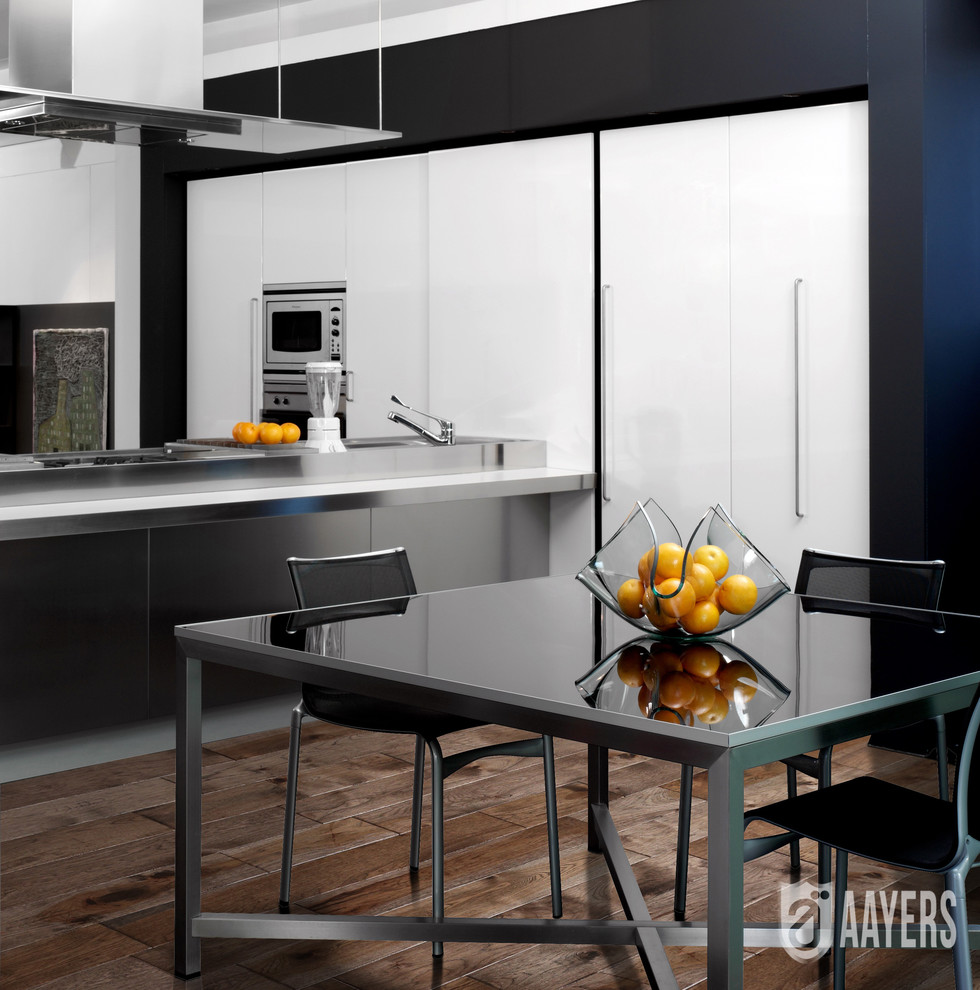 Foto på ett mellanstort funkis kök, med en dubbel diskho, släta luckor, vita skåp, bänkskiva i rostfritt stål, rostfria vitvaror, ljust trägolv och en köksö