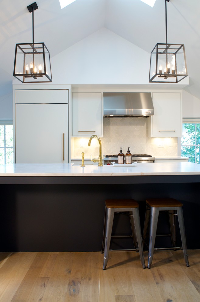Foto de cocina moderna con fregadero sobremueble, armarios con paneles lisos, electrodomésticos con paneles, suelo de madera clara y una isla
