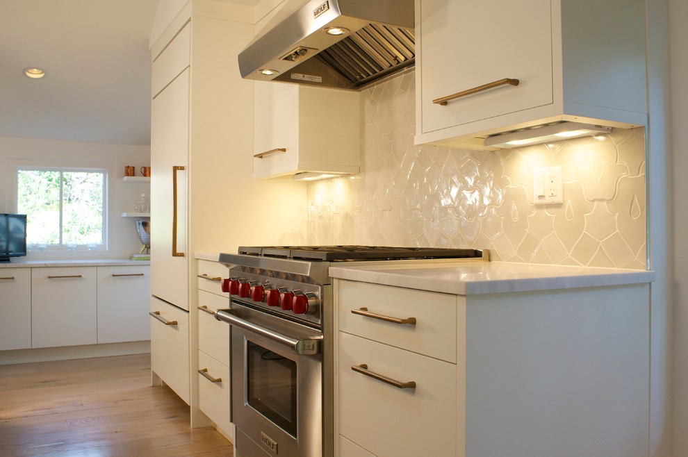 Immagine di una cucina minimalista con lavello stile country, ante lisce, elettrodomestici da incasso e parquet chiaro
