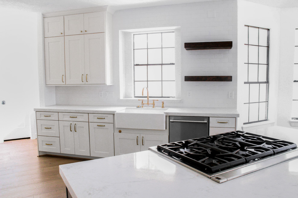 Idéer för ett mellanstort modernt vit kök, med en rustik diskho, luckor med infälld panel, vita skåp, bänkskiva i kvarts, vitt stänkskydd, stänkskydd i tunnelbanekakel, rostfria vitvaror, ljust trägolv, en köksö och gult golv