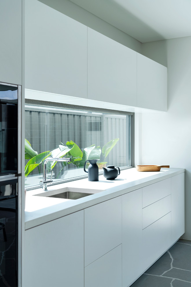Cette photo montre une cuisine ouverte parallèle tendance de taille moyenne avec des portes de placard blanches, un plan de travail en béton et îlot.