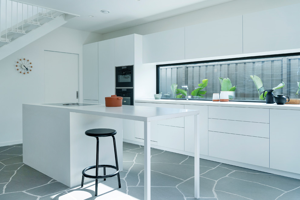 Imagen de cocina moderna de tamaño medio abierta con puertas de armario blancas, encimera de cemento y una isla