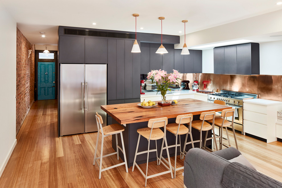 Offene Moderne Küche in L-Form mit flächenbündigen Schrankfronten, grauen Schränken, Küchenrückwand in Metallic, Küchengeräten aus Edelstahl, braunem Holzboden, Kücheninsel und braunem Boden in Melbourne