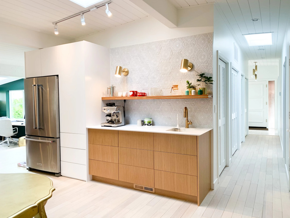 На фото: кухня в стиле ретро с плоскими фасадами, светлыми деревянными фасадами, островом и серым полом с
