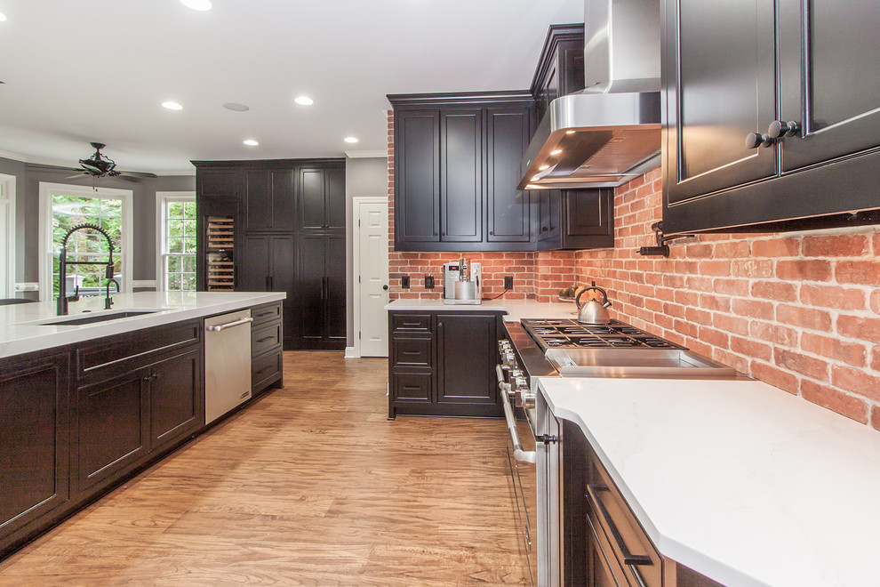 Klassische Küche in U-Form mit flächenbündigen Schrankfronten, schwarzen Schränken, Rückwand aus Backstein, Küchengeräten aus Edelstahl, braunem Holzboden und Kücheninsel in Atlanta