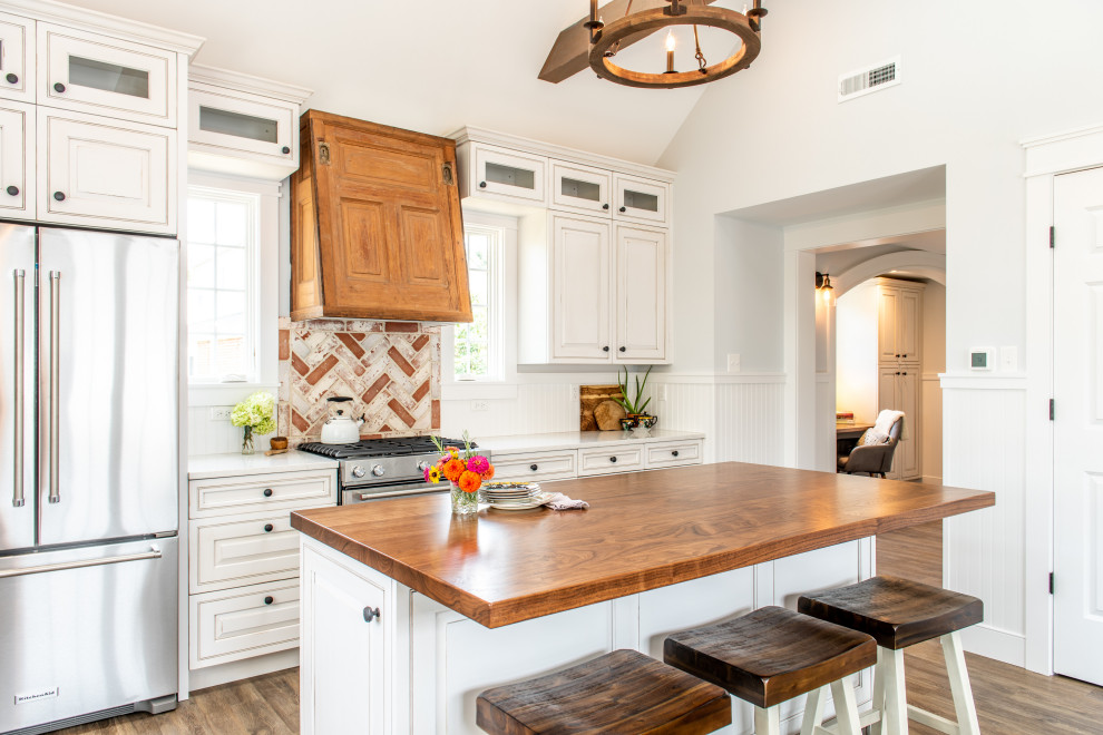Large elegant galley dark wood floor, brown floor and vaulted ceiling kitchen photo in Philadelphia with wood countertops, an island, raised-panel cabinets, white cabinets, white backsplash, wood backsplash, stainless steel appliances and white countertops