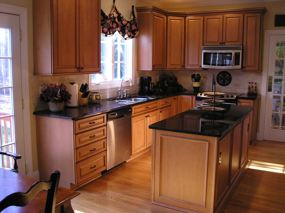 Esempio di un cucina con isola centrale chic con elettrodomestici in acciaio inossidabile, lavello sottopiano, ante in legno scuro e top in granito