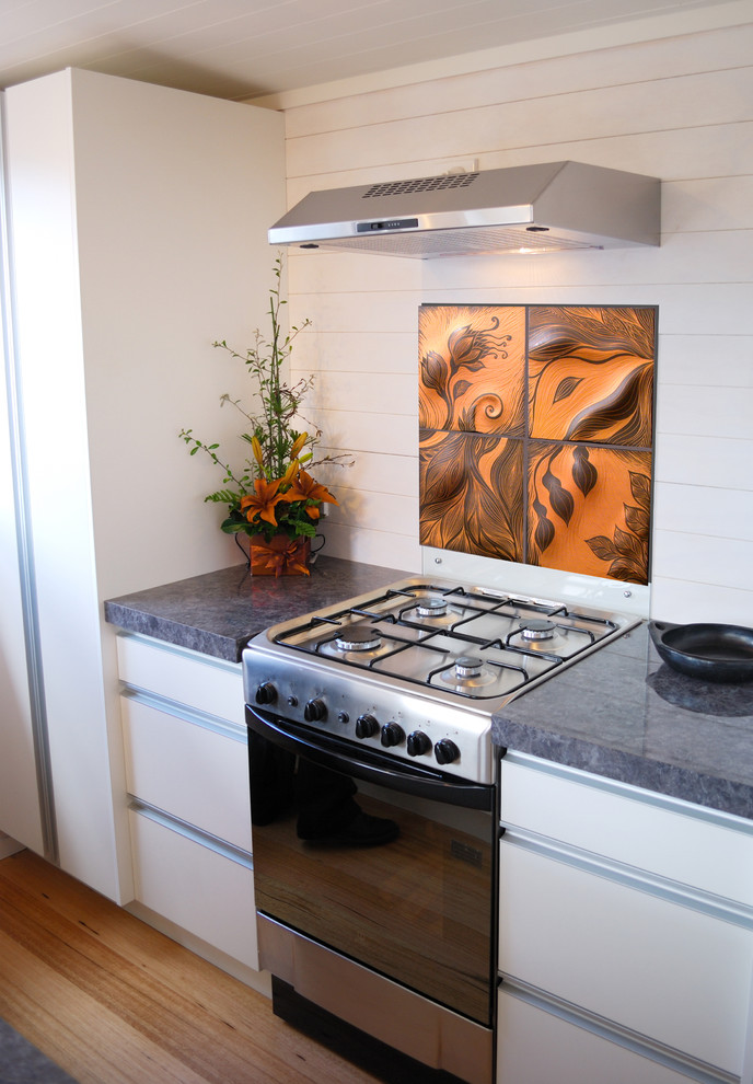 Immagine di una cucina contemporanea con ante lisce, ante bianche, elettrodomestici in acciaio inossidabile e paraspruzzi arancione