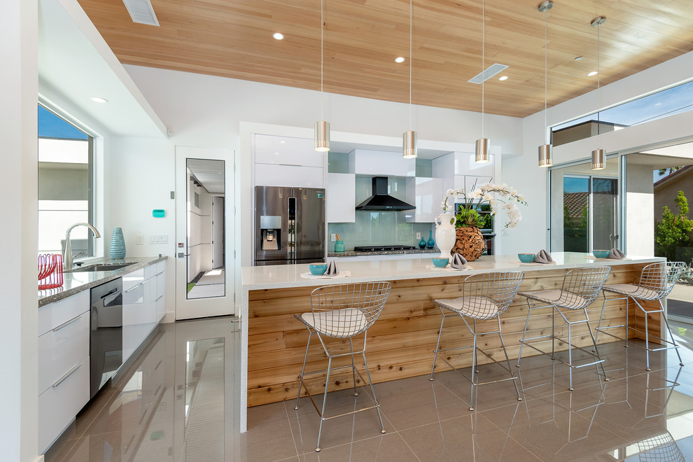 Immagine di una cucina minimalista con ante lisce, ante bianche, paraspruzzi blu, paraspruzzi con lastra di vetro, elettrodomestici in acciaio inossidabile, pavimento multicolore e top bianco