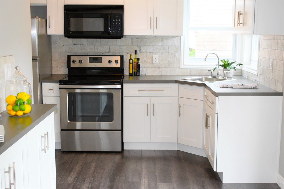 Inspiration for a small rustic l-shaped open plan kitchen in Toronto with a built-in sink, shaker cabinets, white cabinets, quartz worktops, white splashback, ceramic splashback, stainless steel appliances and medium hardwood flooring.