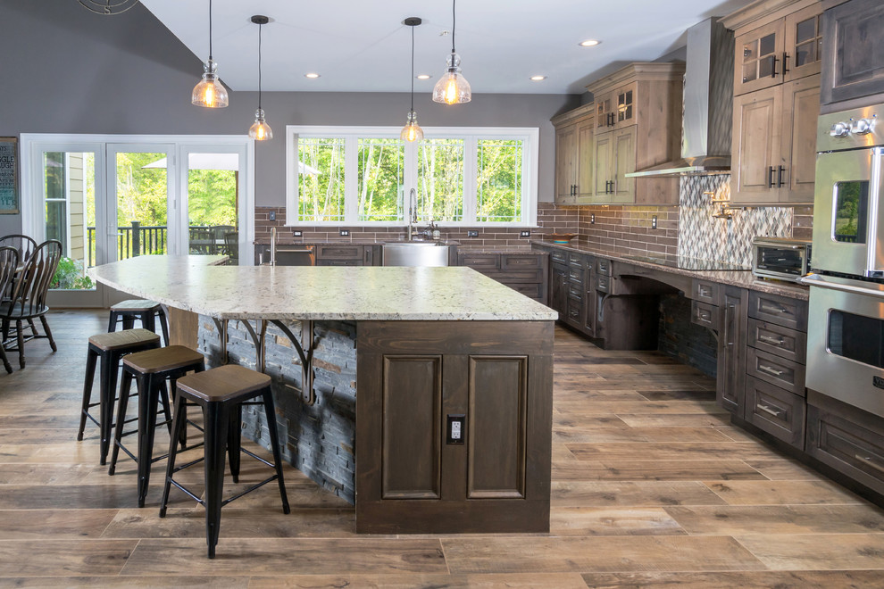 Inspiration for a large rustic l-shaped open plan kitchen in Philadelphia with a belfast sink, raised-panel cabinets, distressed cabinets, engineered stone countertops, grey splashback, cement tile splashback, stainless steel appliances, porcelain flooring, an island and brown floors.