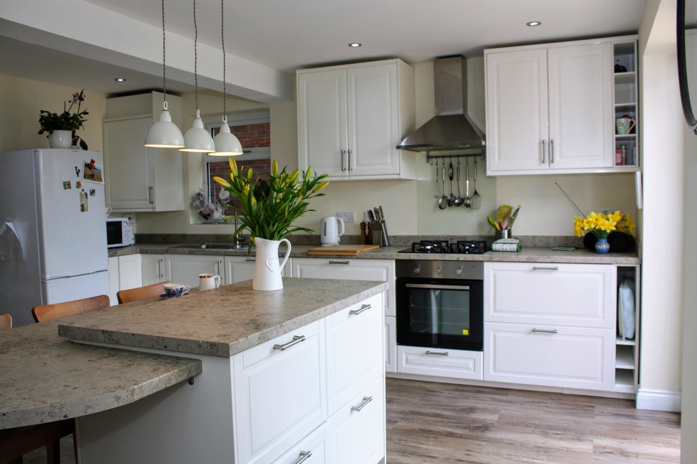 Cette image montre une cuisine design en L avec un placard à porte shaker, des portes de placard blanches, une crédence grise, îlot et un plan de travail gris.
