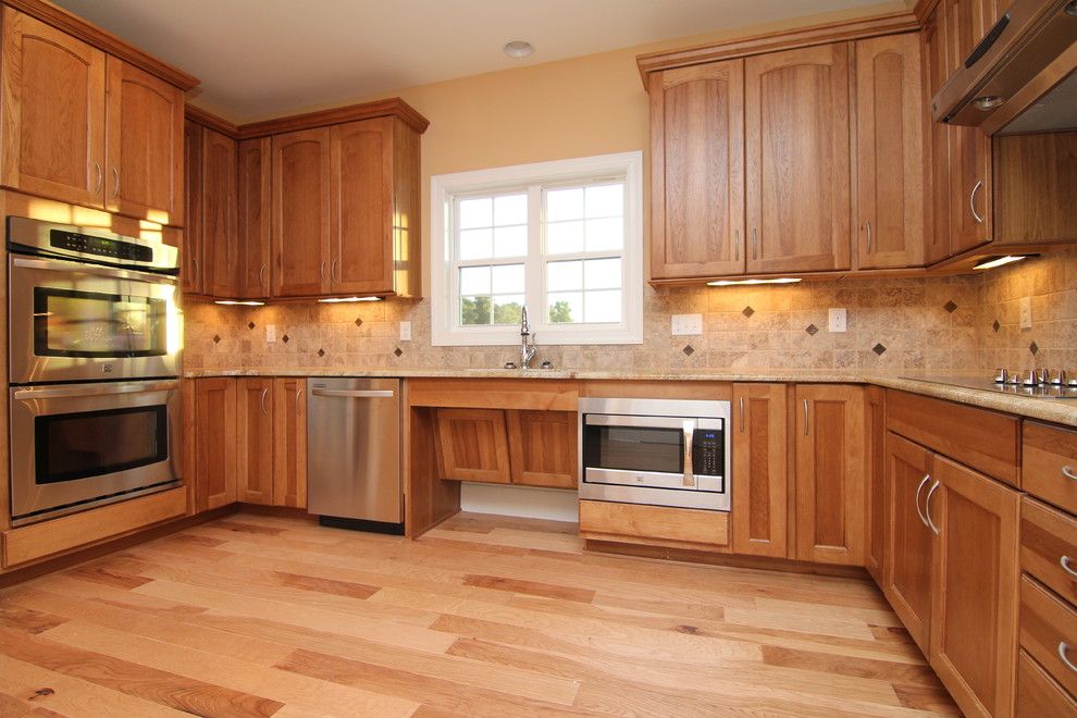 Inspiration for a mid-sized timeless u-shaped light wood floor enclosed kitchen remodel in Raleigh with an undermount sink, recessed-panel cabinets, light wood cabinets, granite countertops, multicolored backsplash, ceramic backsplash, stainless steel appliances and no island