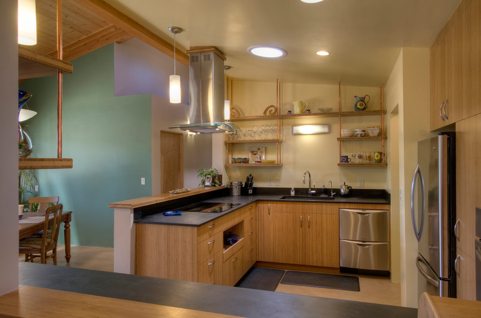 Ejemplo de cocina actual con armarios con paneles lisos, puertas de armario de madera clara y electrodomésticos de acero inoxidable