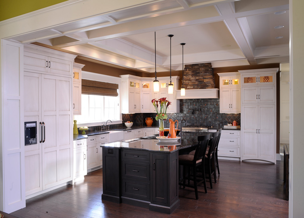 Eat-in kitchen - traditional l-shaped dark wood floor and coffered ceiling eat-in kitchen idea in Columbus with white cabinets, black backsplash, shaker cabinets, stainless steel appliances, an island, black countertops and a farmhouse sink