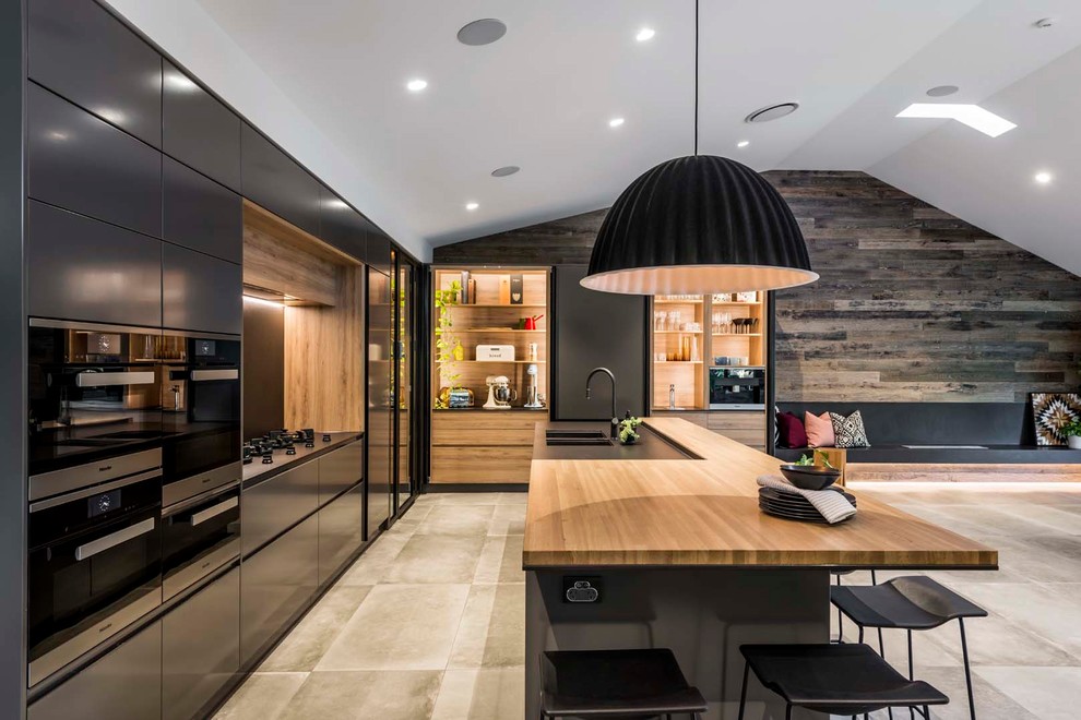 Moderne Wohnküche in L-Form mit Unterbauwaschbecken, schwarzen Schränken, Arbeitsplatte aus Holz, Küchenrückwand in Schwarz, schwarzen Elektrogeräten, Porzellan-Bodenfliesen, Kücheninsel, grauem Boden und flächenbündigen Schrankfronten in Brisbane