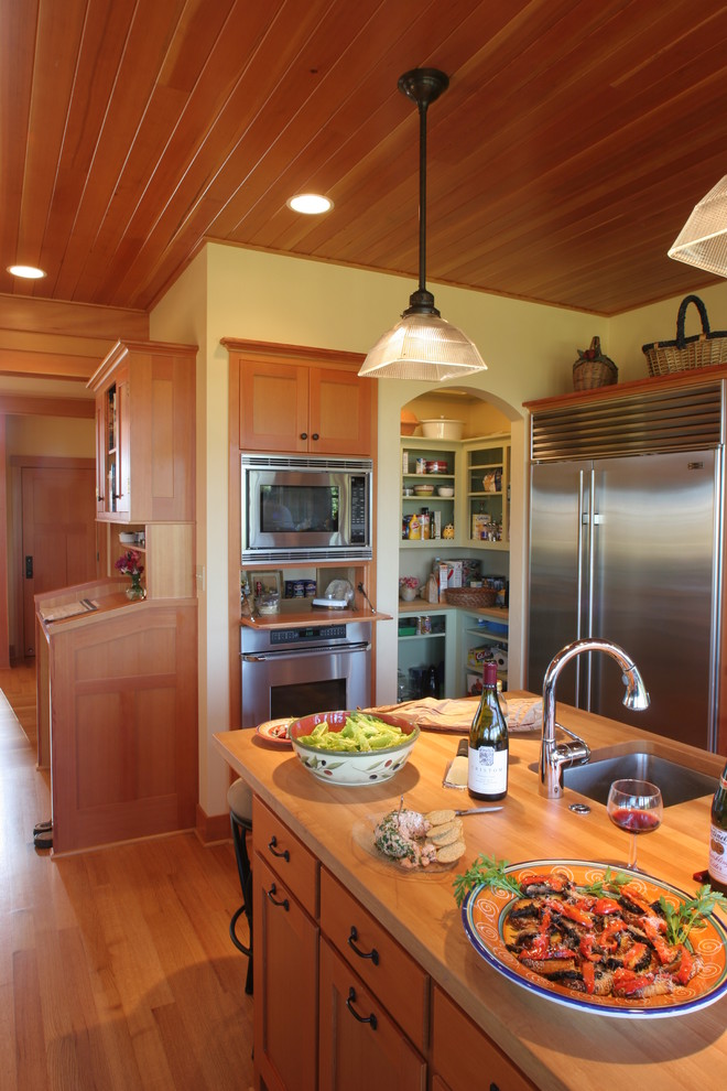 На фото: кухня в классическом стиле с деревянной столешницей, техникой из нержавеющей стали и телевизором