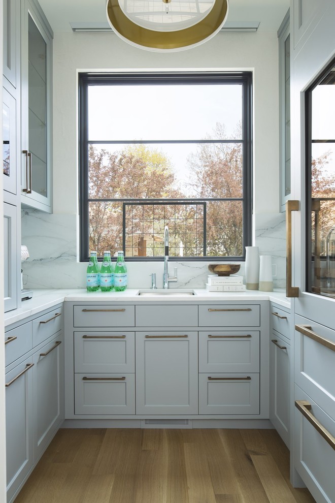 Bild på ett stort vintage vit vitt kök, med en undermonterad diskho, skåp i shakerstil, grå skåp, marmorbänkskiva, vitt stänkskydd, stänkskydd i marmor, integrerade vitvaror, ljust trägolv, beiget golv och en köksö
