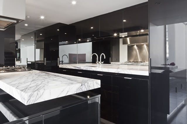 Exemple d'une cuisine moderne avec des portes de placard noires, plan de travail en marbre, un électroménager en acier inoxydable et îlot.