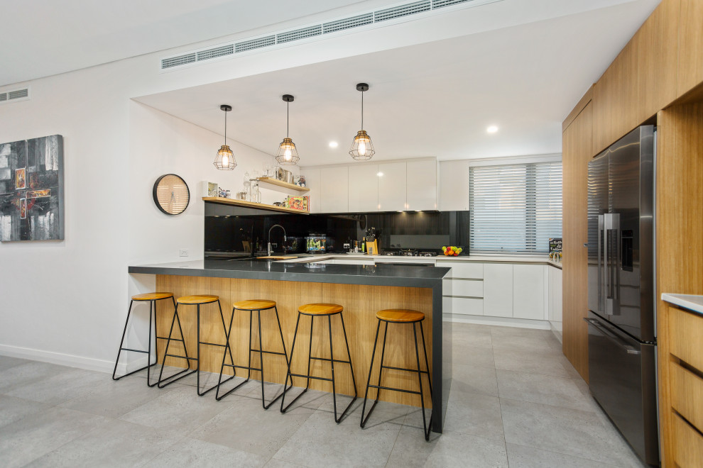 Inspiration for a contemporary u-shaped gray floor kitchen remodel in Perth with flat-panel cabinets, white cabinets, black appliances, a peninsula and white countertops