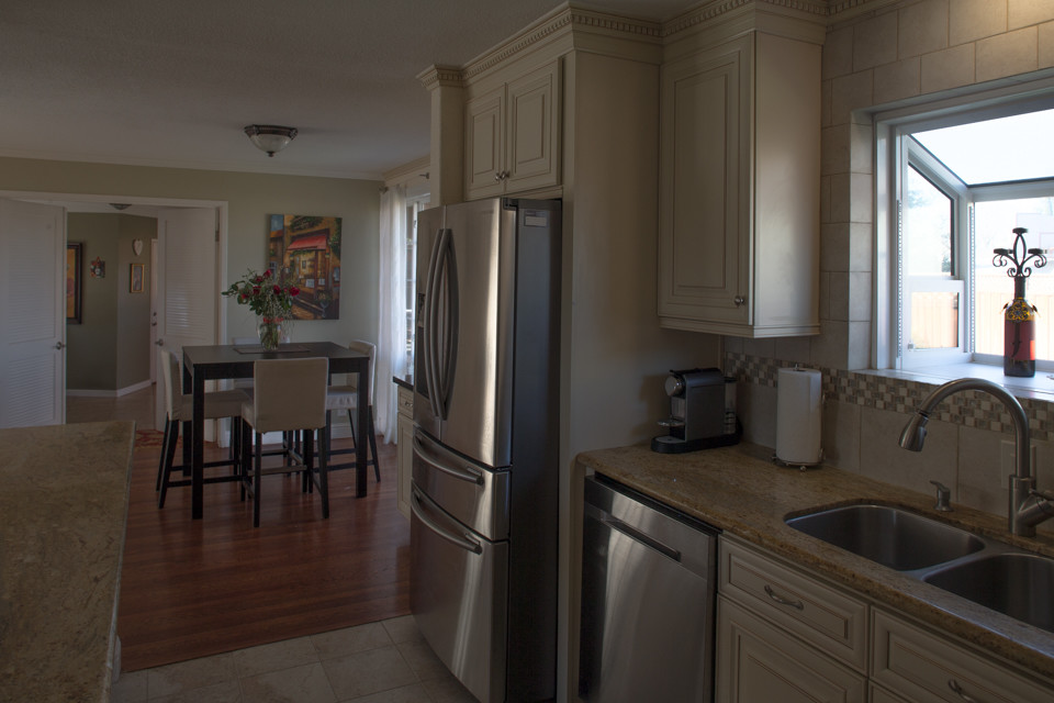 Idéer för att renovera ett mellanstort funkis kök, med en dubbel diskho, vita skåp, rostfria vitvaror, luckor med upphöjd panel, granitbänkskiva och beige stänkskydd