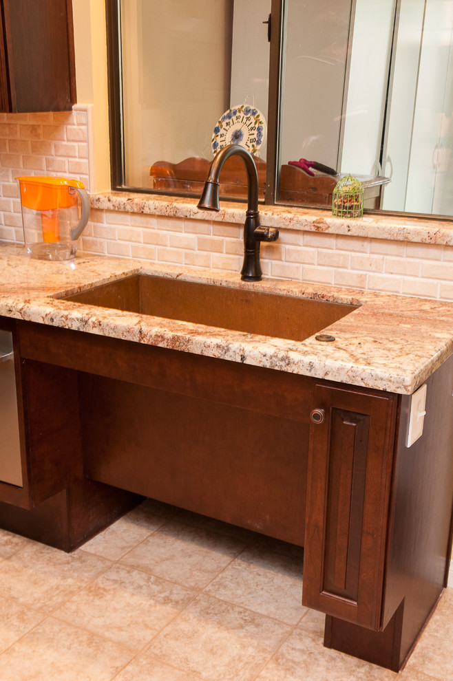 Example of a mid-sized trendy l-shaped porcelain tile and beige floor enclosed kitchen design in Other with an undermount sink, raised-panel cabinets, dark wood cabinets, granite countertops, beige backsplash, stone tile backsplash, stainless steel appliances and no island