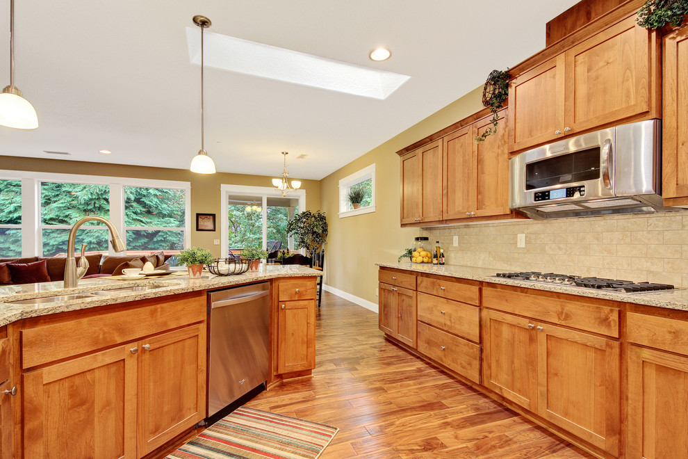 Inspiration for a mid-sized timeless u-shaped dark wood floor open concept kitchen remodel in Portland with a double-bowl sink, shaker cabinets, medium tone wood cabinets, granite countertops, beige backsplash, subway tile backsplash, stainless steel appliances and an island