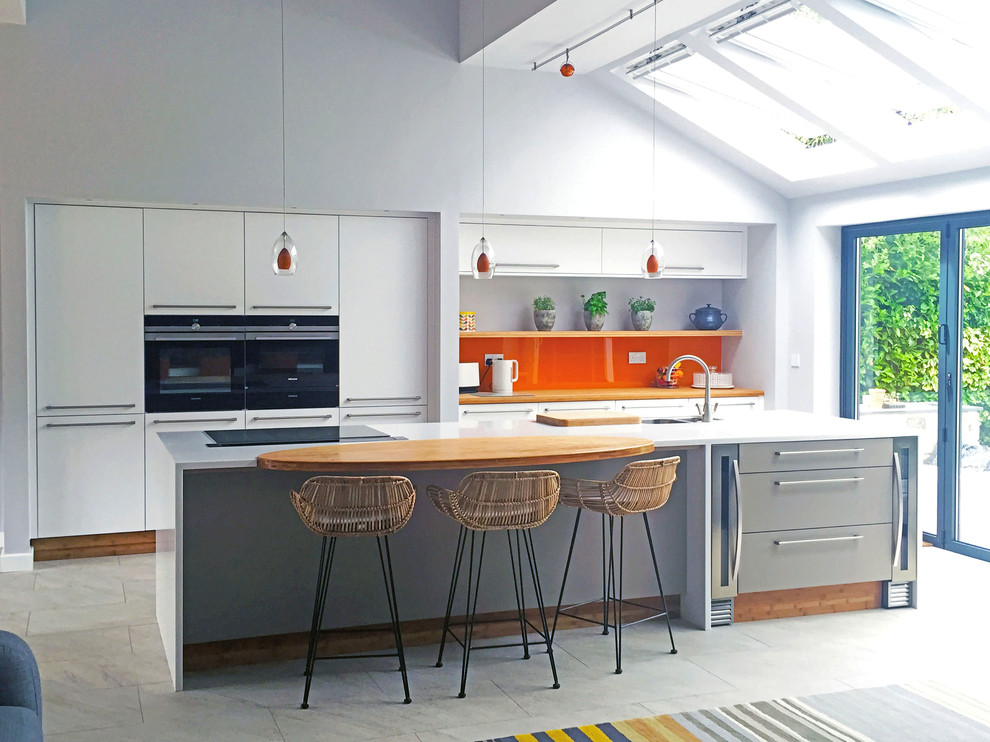 Idéer för ett stort modernt kök med öppen planlösning, med en integrerad diskho, släta luckor, orange stänkskydd, glaspanel som stänkskydd, svarta vitvaror och en köksö