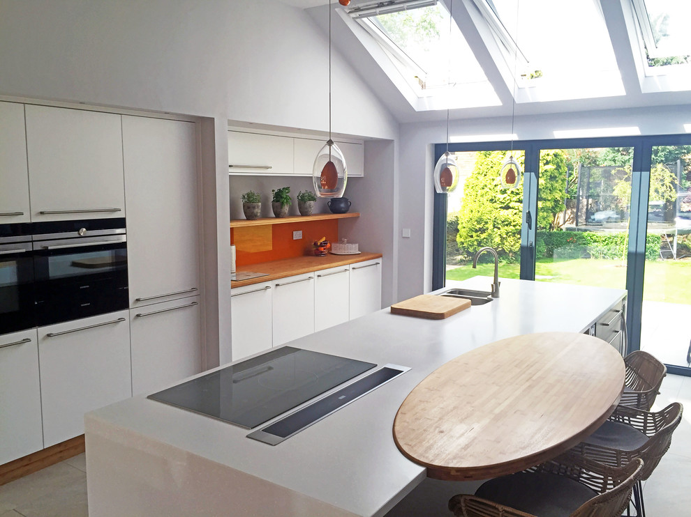 Exempel på ett stort modernt kök med öppen planlösning, med en integrerad diskho, släta luckor, orange stänkskydd, glaspanel som stänkskydd, svarta vitvaror och en köksö
