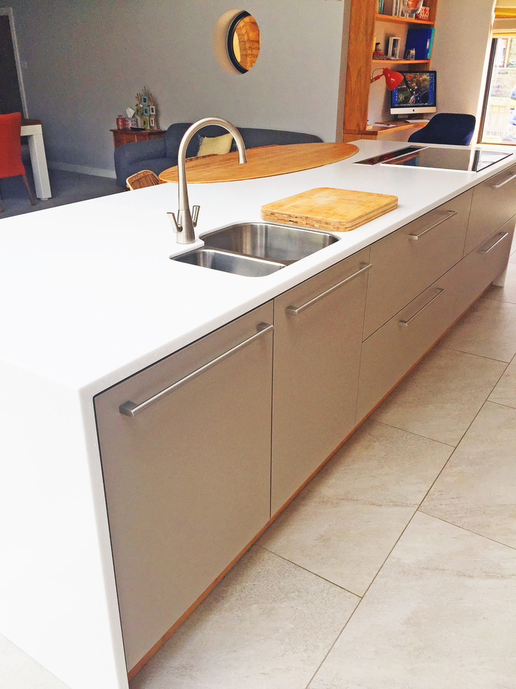 Foto de cocina moderna grande abierta con fregadero integrado, armarios con paneles lisos, salpicadero naranja, salpicadero de vidrio templado, electrodomésticos negros y una isla