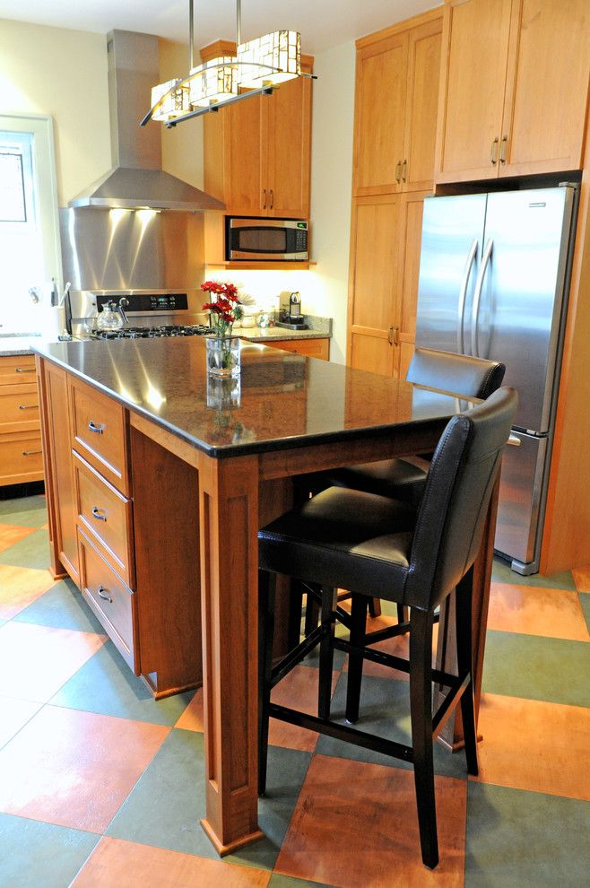 Exemple d'une cuisine linéaire chic en bois brun fermée et de taille moyenne avec un placard à porte shaker, un plan de travail en granite, un électroménager en acier inoxydable, un sol en carrelage de porcelaine, îlot et un sol multicolore.
