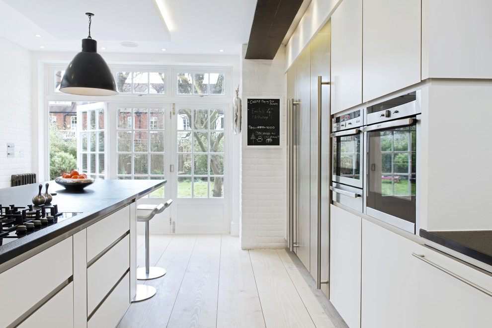 Bild på ett stort skandinaviskt kök, med släta luckor, vita skåp, ljust trägolv och en köksö